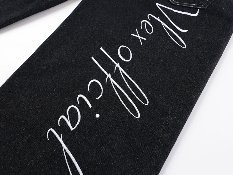 Close-up of black denim pant leg with white script print