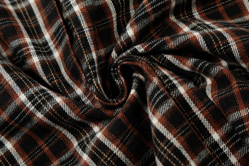 Close-up of distressed brown, black and white plaid shirt fabric with raw edge texture and soft folds