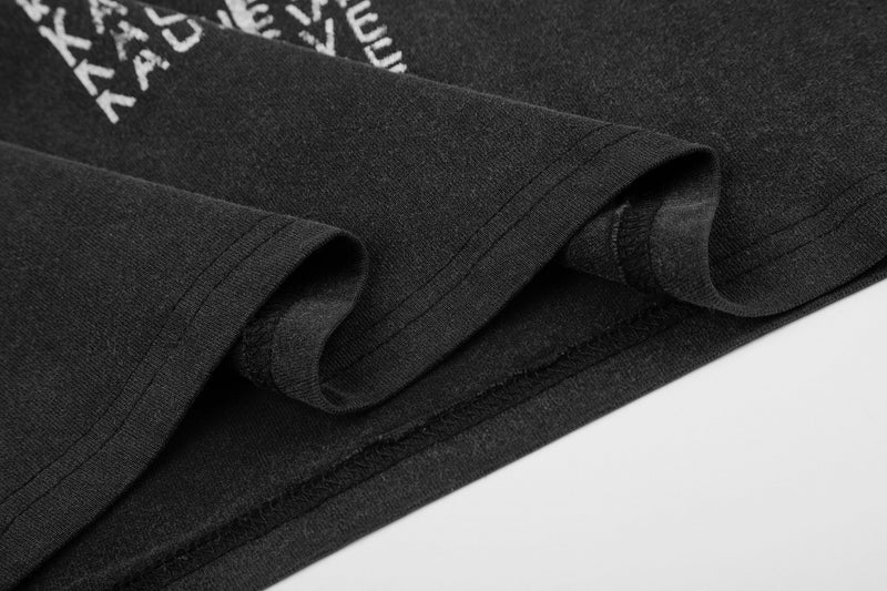 Black vintage graphic tee with folded sleeves and distressed cross print detail on soft streetwear fabric