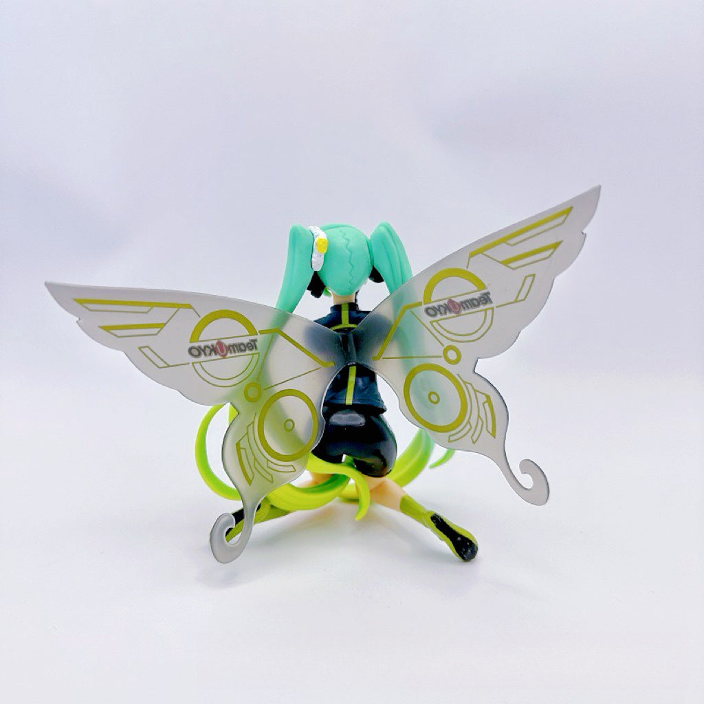 Standing against a white backdrop, the Racing Butterfly Hatsune Miku 12cm PVC Figure from Team MIKYO features mint green hair and metallic butterfly wings with &quot;Onomot&quot;-like circular designs. Dressed in a black outfit with vivid green accents, she&