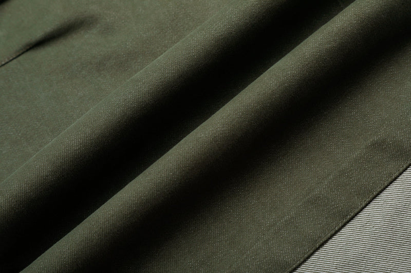 Close-up of army green fabric with visible twill texture and seam