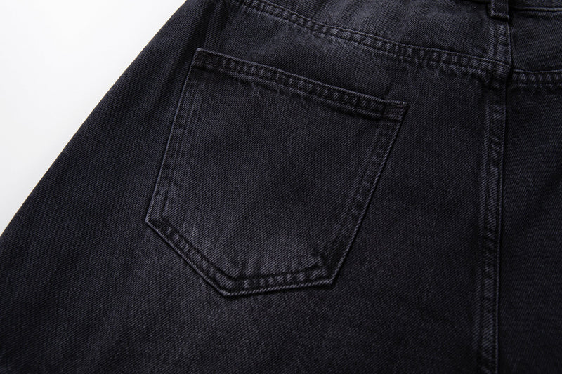 Close-up of back pocket on dark wash jeans with topstitched edge