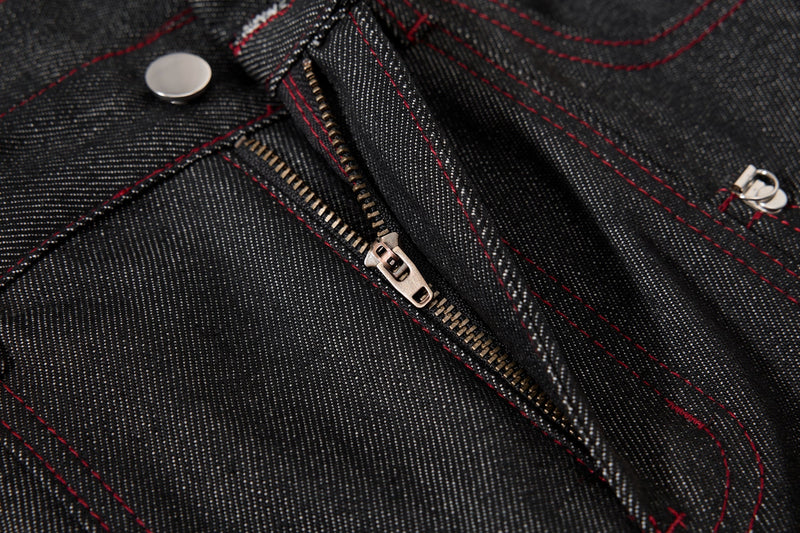 Close-up of black denim zipper fly with red contrast stitching and metal zipper