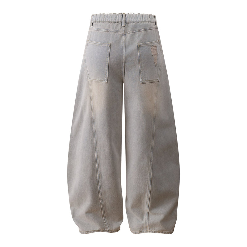 Back view of light wash wide-leg jeans with patch pockets and distressed tear on one pocket
