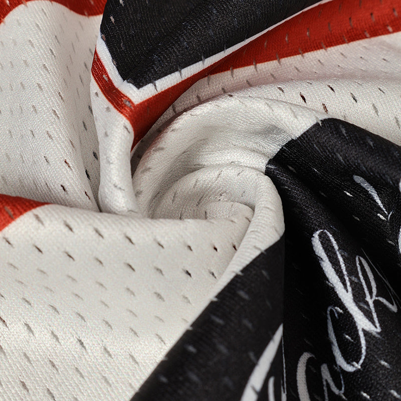 Close-up of white football jersey fabric with black, red and white graphic details and stitched mesh texture
