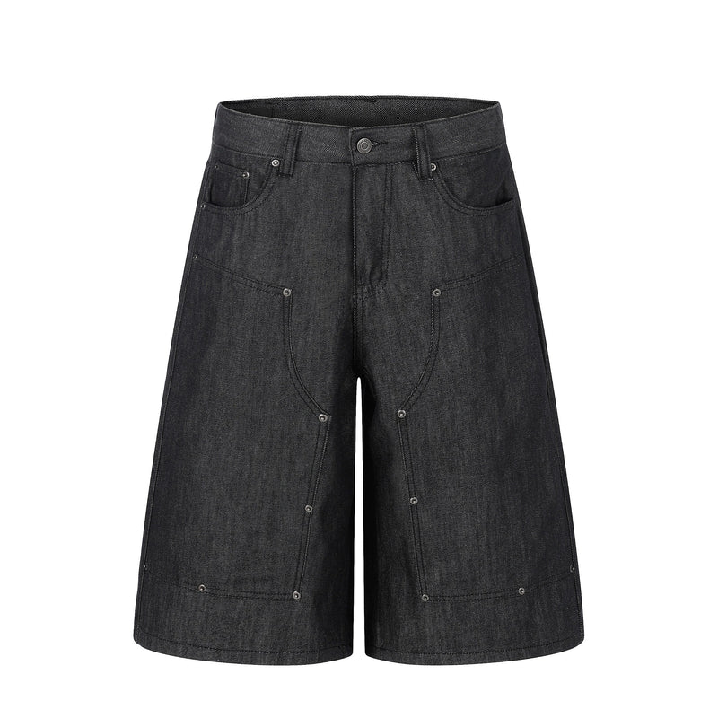 Front view of black raw denim baggy shorts with wide legs and silver rivet details