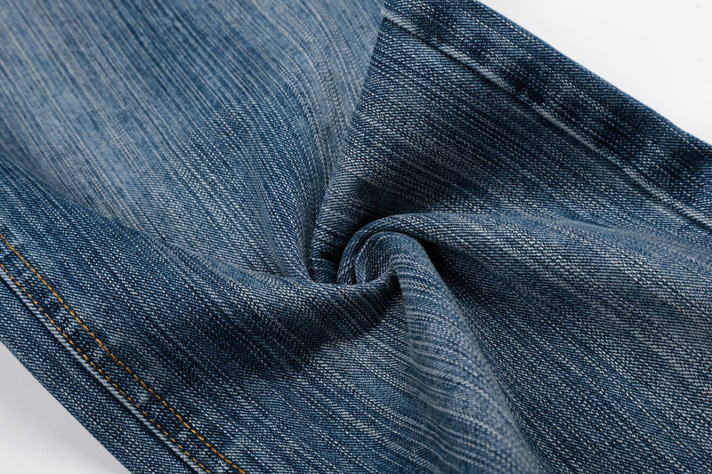 Close-up of folded blue denim fabric showing grainy texture and stitched seam