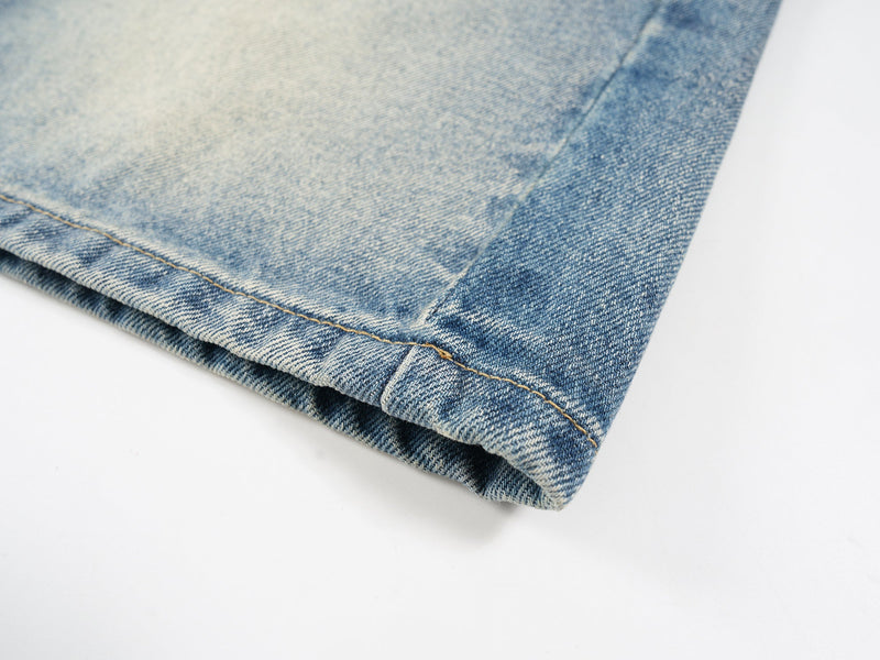 Close-up of rolled-looking cuff hem and stitching on light wash denim shorts