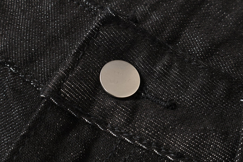 Close-up of black denim waistband snap button and seam detail
