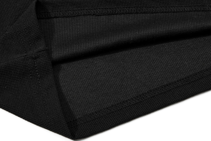 Black polo shirt fabric close-up with ribbed texture and neat stitched hems, showing a streetwear gothic style