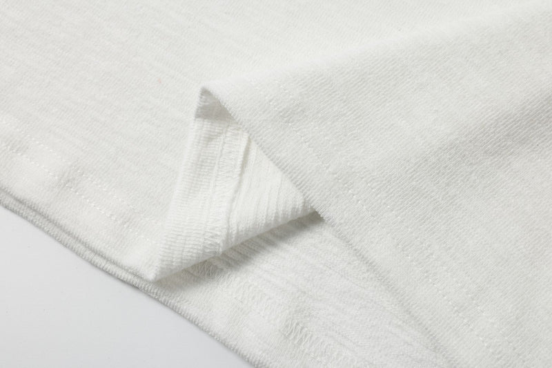 Close-up of white textured polo shirt fabric with folded sleeve and stitched hem details