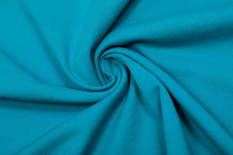 Turquoise knit fabric close-up with a soft spiral fold, showing the texture of an athletic color block T-shirt