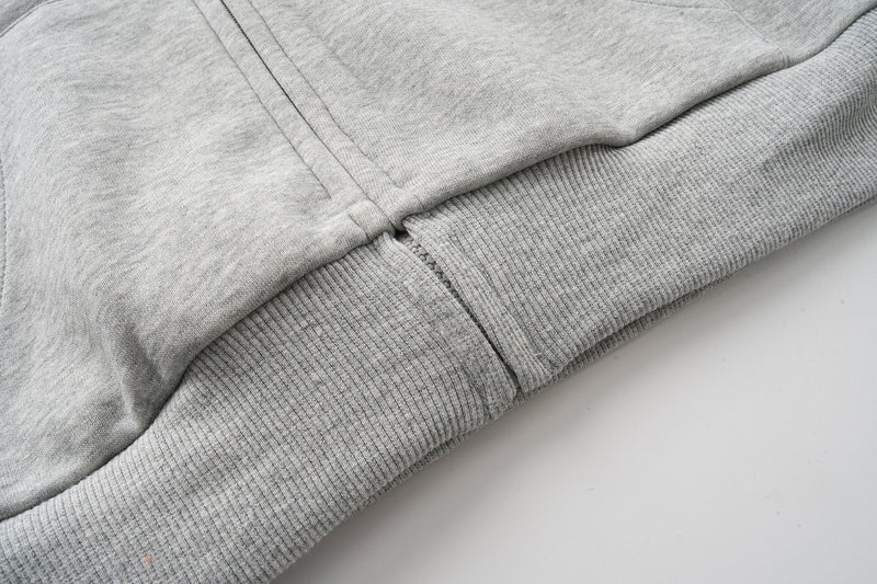 Lower front hem close-up of heather grey hoodie with ribbed waistband and zipper edge