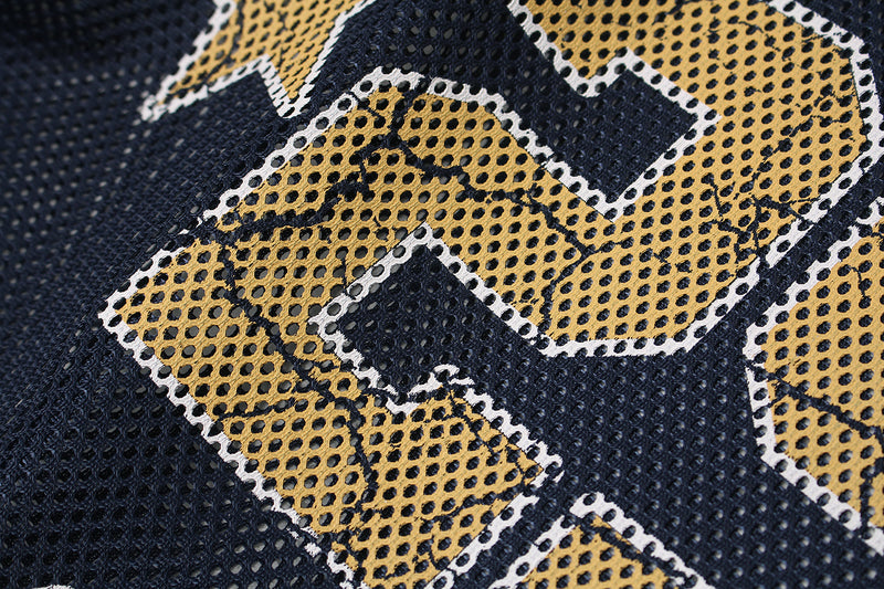 Close-up of navy mesh jersey fabric with gold flame-style lettering and white trim details