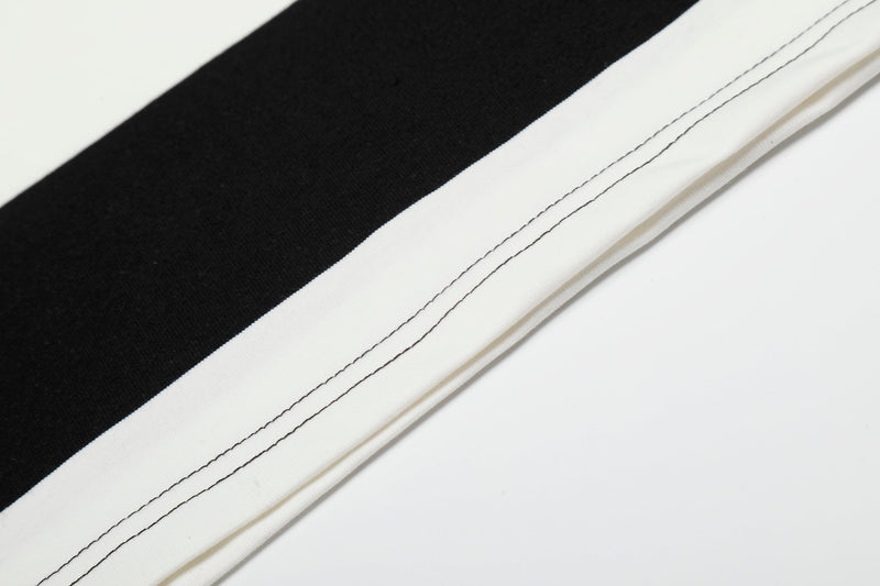 Close-up of black and white rugby stripe polo shirt fabric with contrasting topstitching and clean folded hem