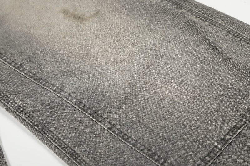 Close-up of gray denim leg panel with faded wash and subtle distressing