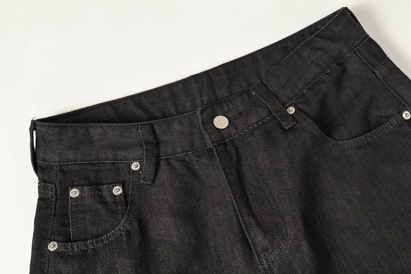 Close-up of the black denim waistband and front pocket with silver rivets