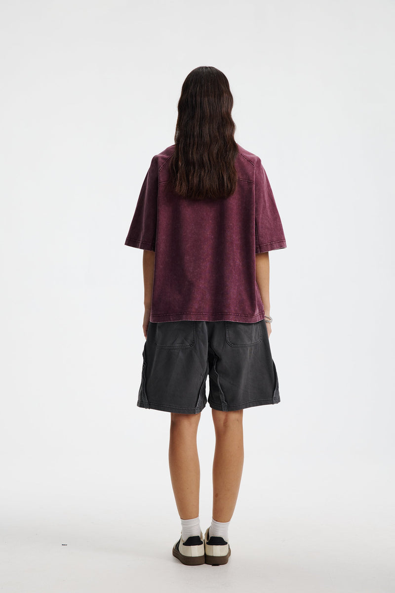 Back view of a vintage washed oversized burgundy cotton T-shirt styled with black shorts and sneakers