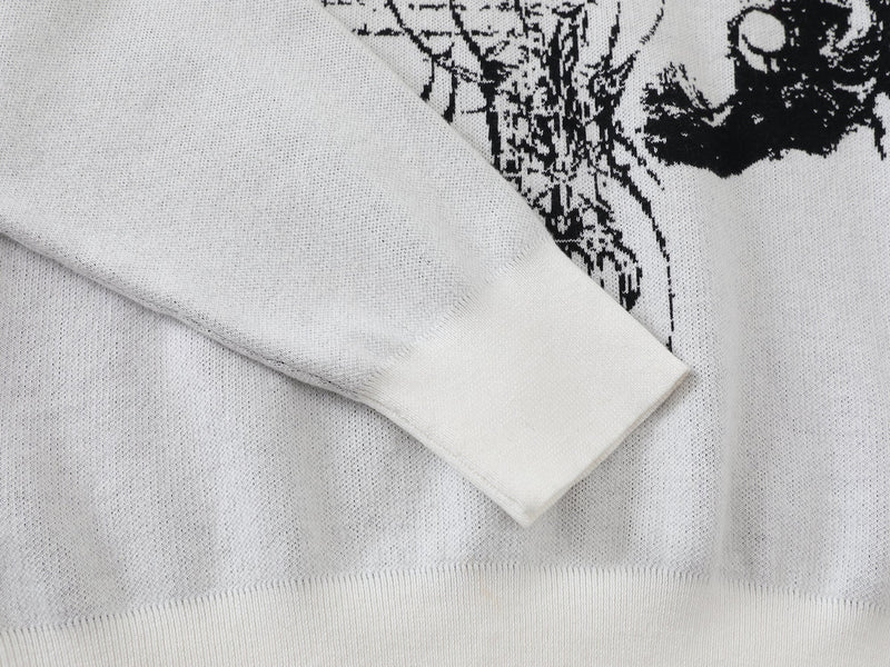 White knit sweater sleeve and front hem with black graphic visible at the edge