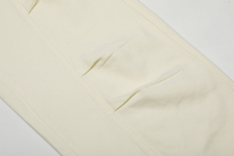 Close-up of cream cargo pants leg fabric with diagonal seam detail