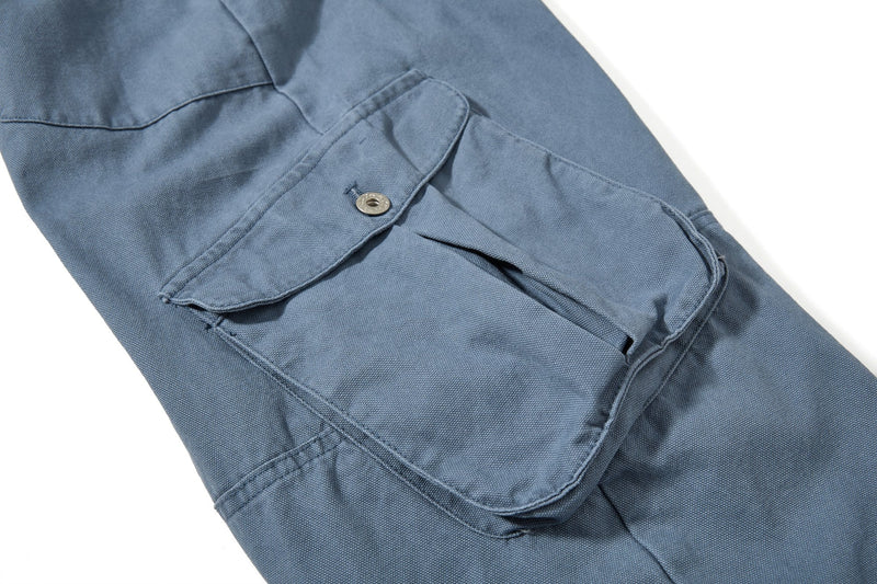 Close-up of blue cargo pant side pocket with buttoned flap