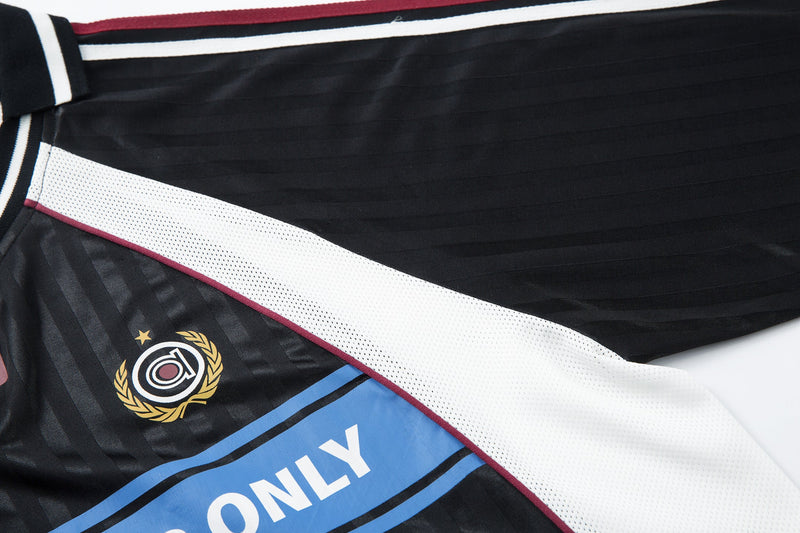 Diagonal close-up of jersey front showing white side panel, crest logo, and blue slogan band
