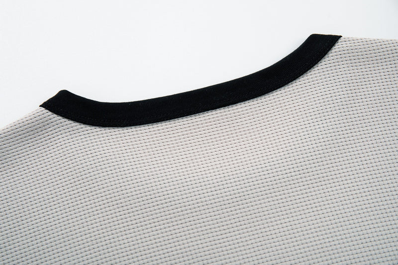 Close-up of a light gray textured ringer T-shirt with black crew neckline, styled for retro punk streetwear