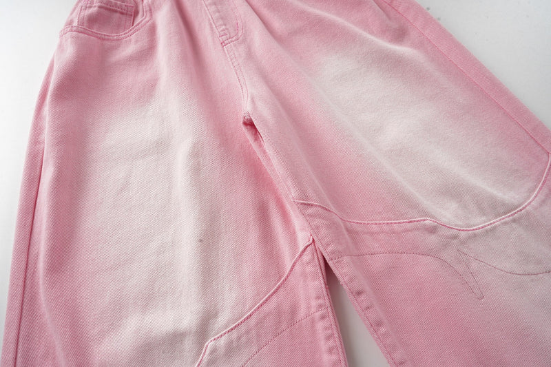 Side close-up of pink washed denim leg with curve seam stitching and faded panel