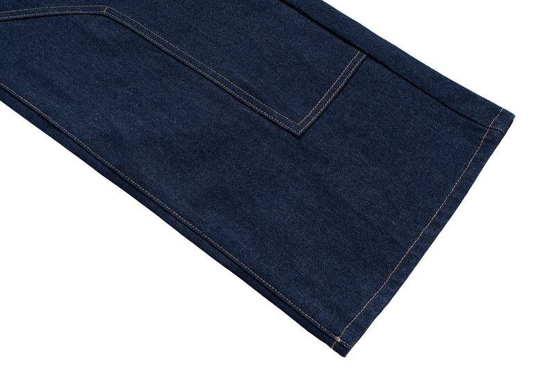 Lower leg close-up of raw indigo denim jeans with hem stitching and wide barrel fit