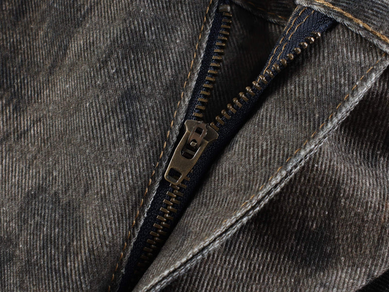 Close-up of zipper fly on dark textured denim jeans with visible stitching