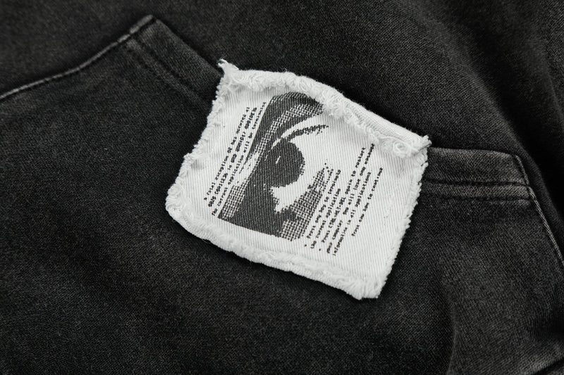 Close-up of frayed white patch with black graphic print on black hoodie