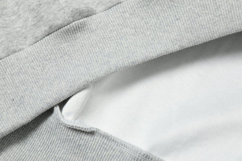 Light gray hoodie hem close-up with ribbed knit waistband and lining edge