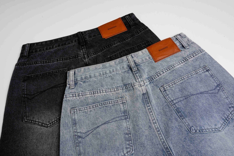 Back waist view of black and light wash wide-leg jeans with leather patches