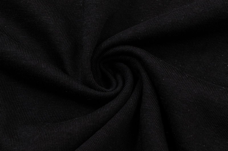 Close-up of black textured fabric with a swirling fold, showcasing an oversized gothic streetwear tee material