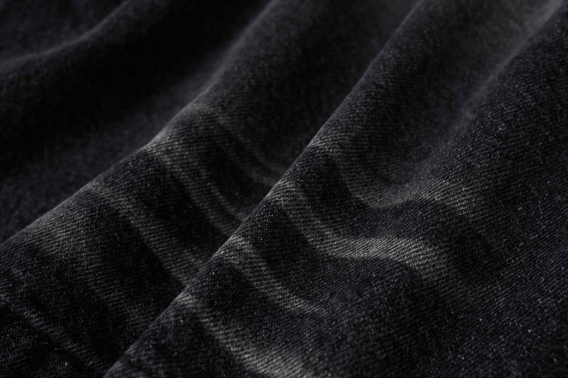 Close-up of black denim fabric with soft faded creases and textured weave