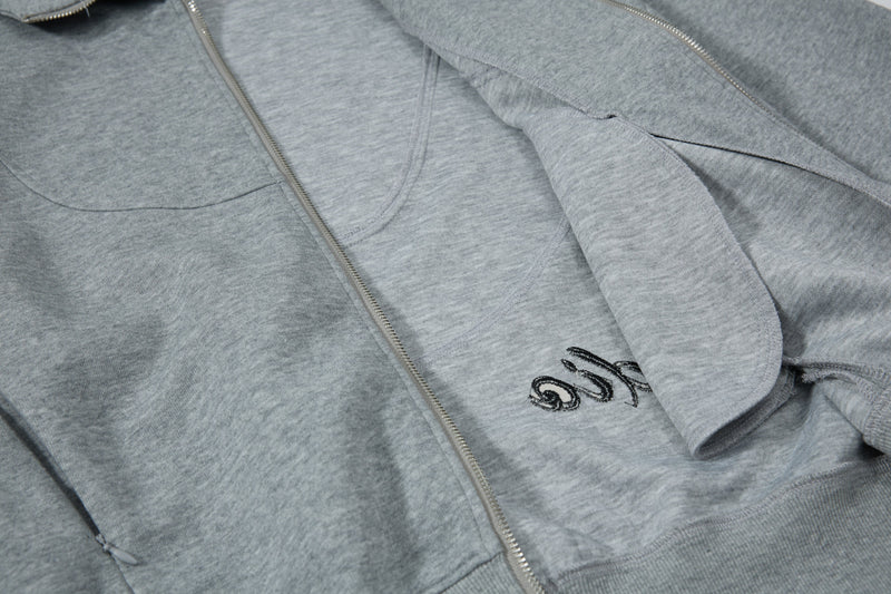 Close-up of gray hoodie front with pocket zipper and partial chest graphic
