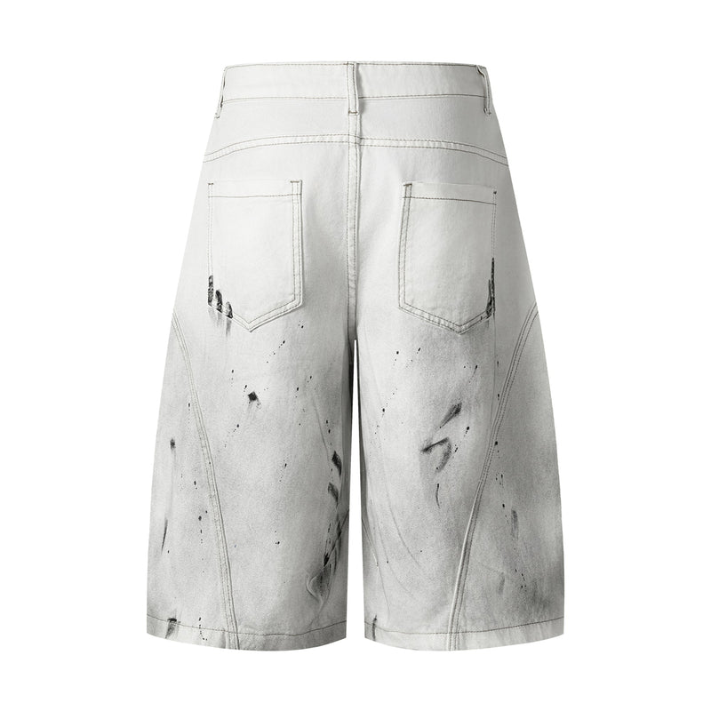 Back view of white wide-leg denim shorts with patch pockets and black distressed splatter