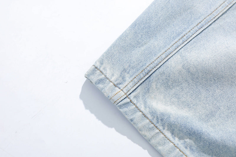 Close-up of hem and stitched cuff on light wash denim jeans