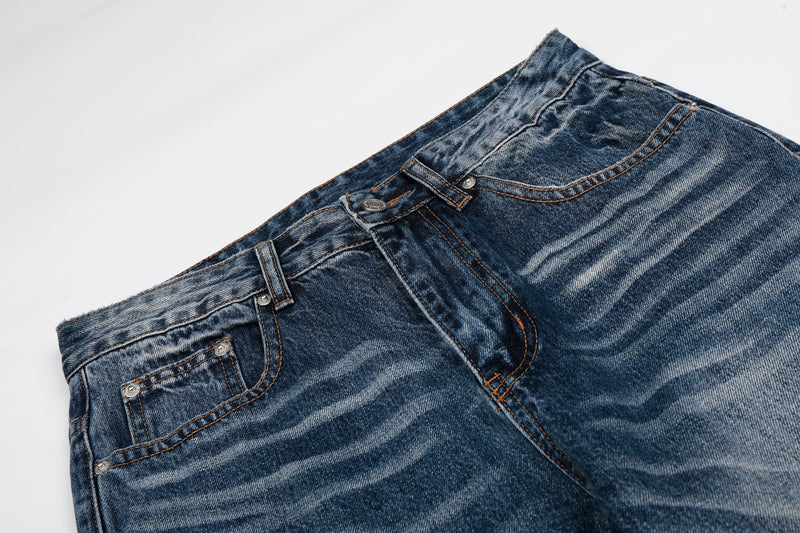 Close-up of the front waist and fly on faded blue denim jeans with contrast stitching
