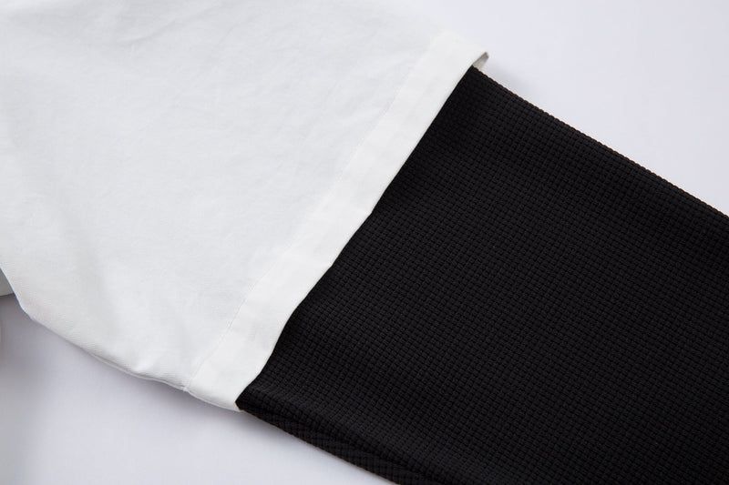 Close-up of white sleeve cuff over black textured long sleeve