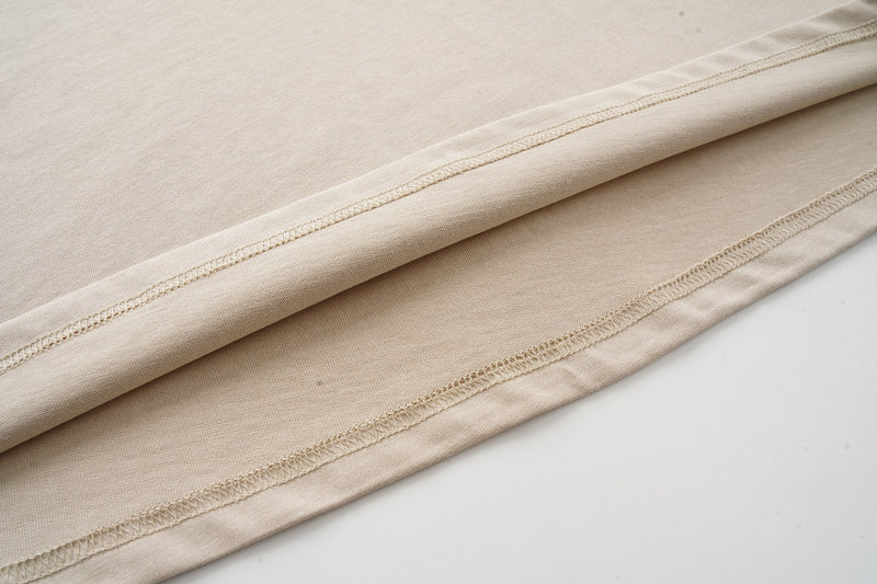 Close-up of beige raglan T-shirt fabric with visible flatlock seams and soft streetwear styling