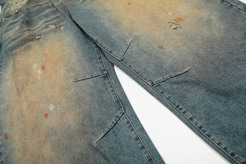 Close-up of distressed denim legs with faded patches and small worn holes