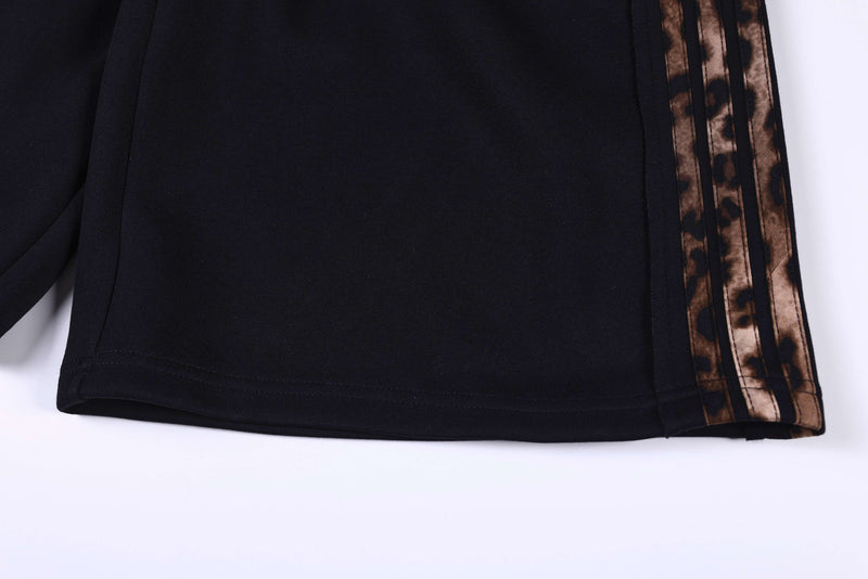 Lower leg close-up of black shorts with leopard stripe along the side hem