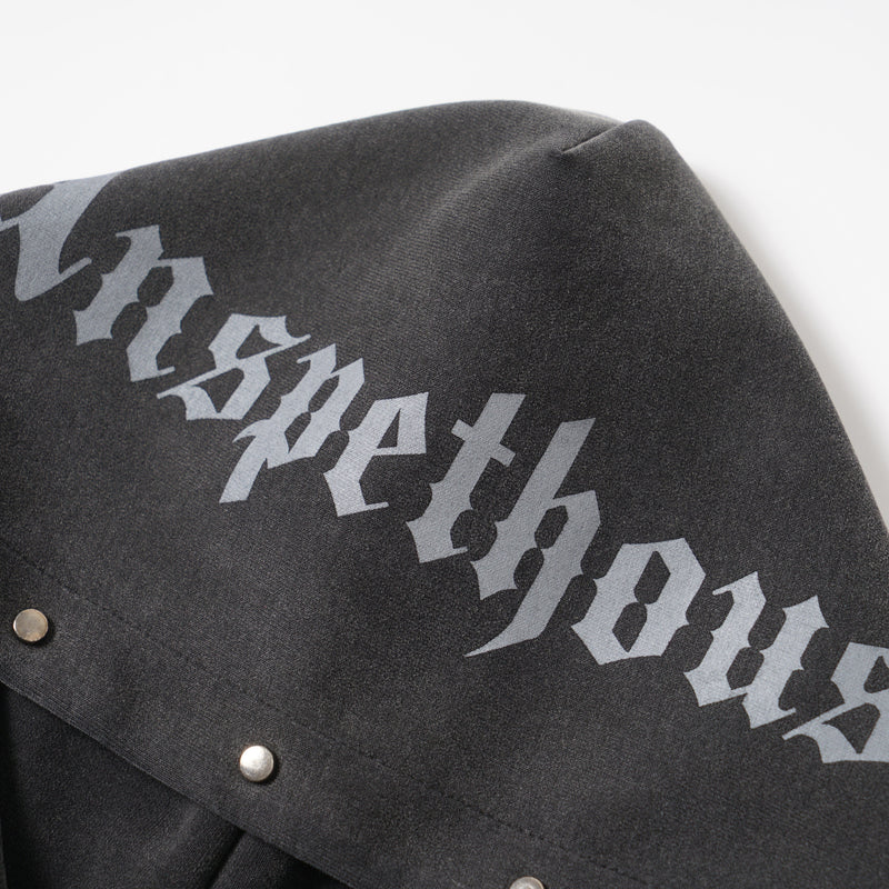 Close-up of hood fabric showing gray gothic lettering on black washed material