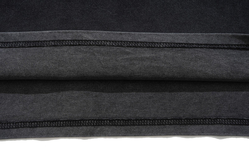 Close-up of black oversized graphic tee hem with layered raw edge stitching and dark streetwear texture