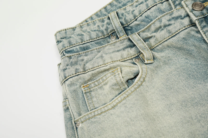 Close-up of front pocket, belt loops, and waistband on faded light wash jeans