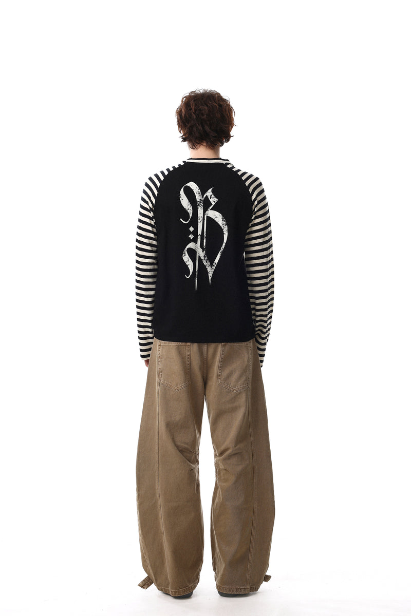 Back view of black raglan tee with cream striped sleeves and white gothic cross graphic