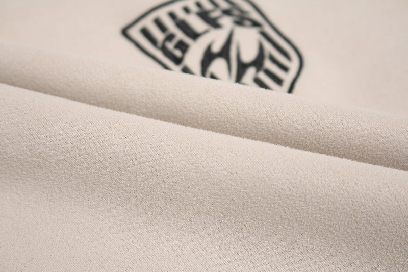Close-up of beige suede-panel T-shirt fabric with a black sporty graphic print