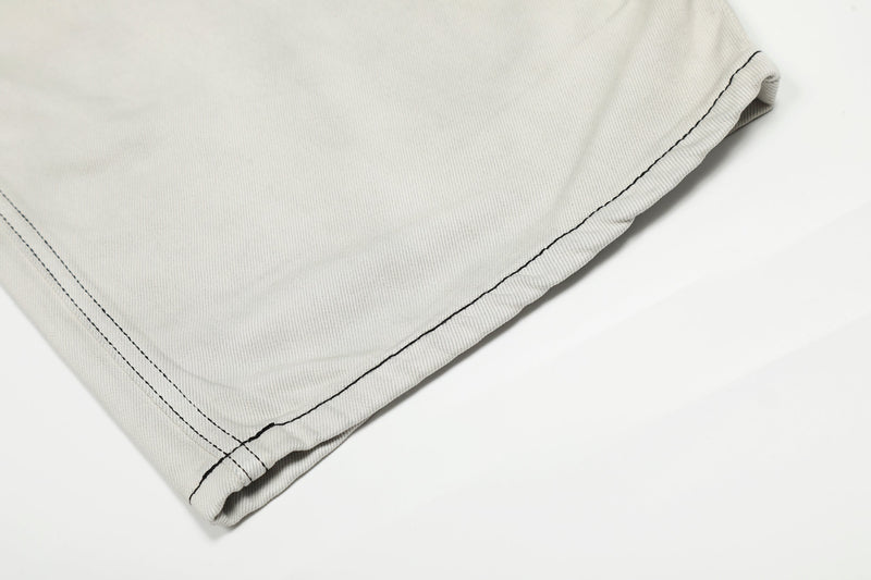 Close-up of hem on light gray wide-leg jeans with contrast stitching