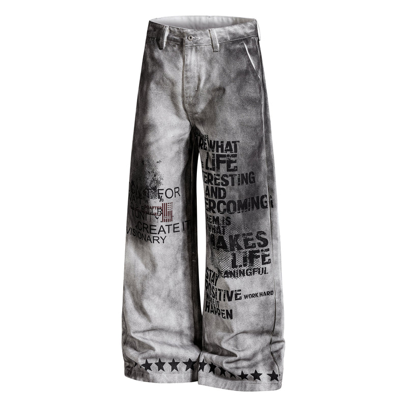 Angled front view of gray washed wide-leg pants with bold black graphic text and stars at the hem